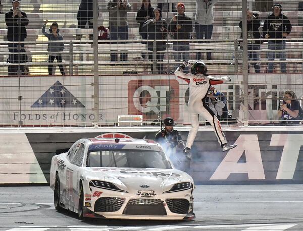 Ty Gibbs leaves his car behind and climbs the fence to celebrate winning the Nalley Cars 250 Xfinity Series Race at Atlanta Motor Speedway in Hampton on Saturday, March 19, 2022. (Hyosub Shin / Hyosub.Shin@ajc.com)