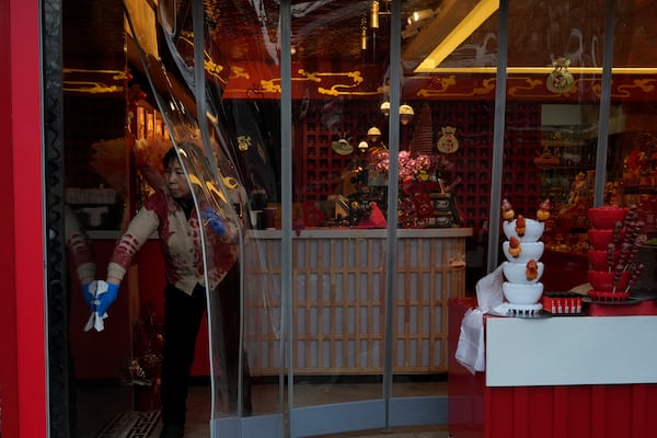 A store workers cleans the doors to a shop ahead of the National People's Congress in Beijing, on Feb. 21, 2025. (AP Photo/Ng Han Guan)