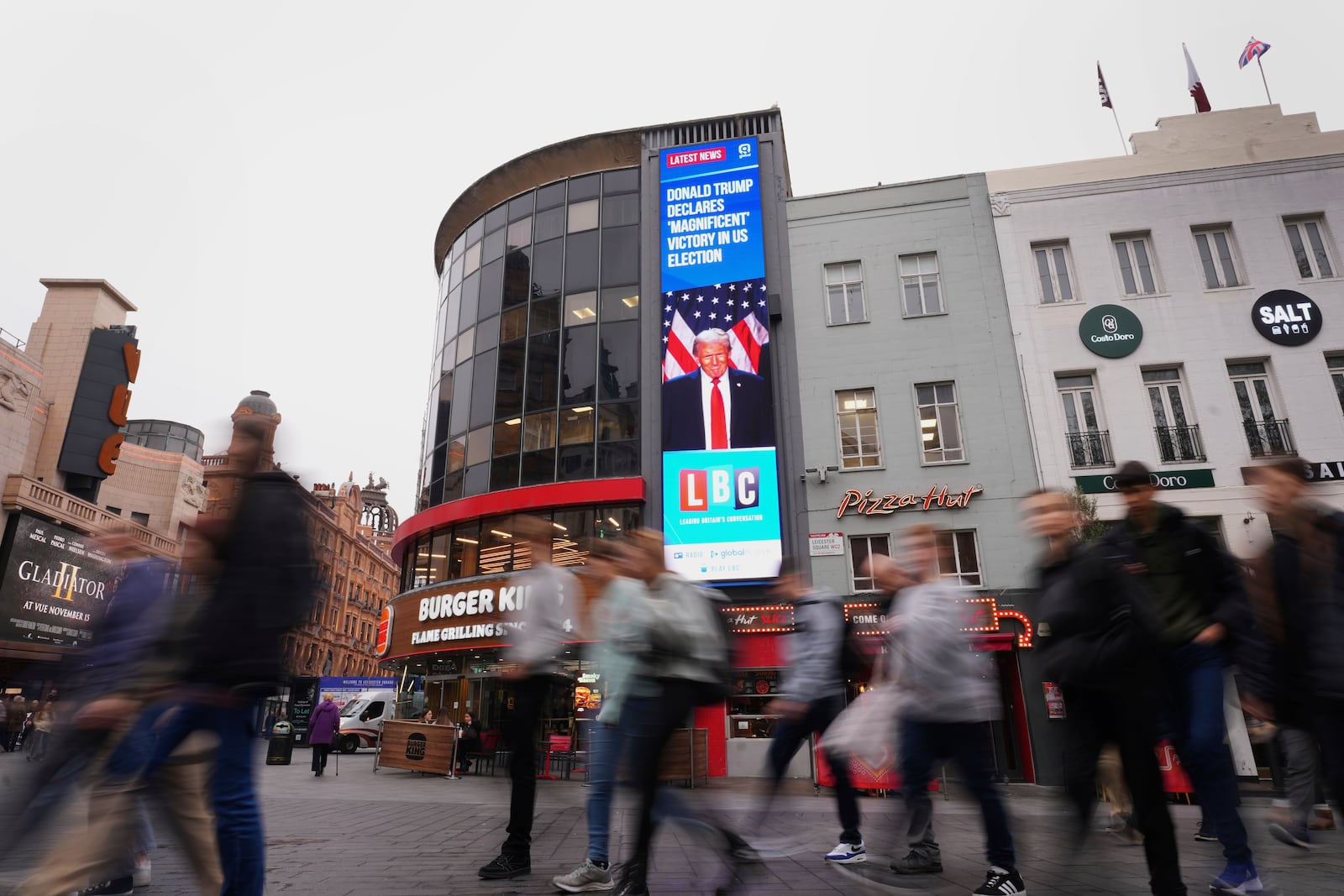 Pedestrians pass a digital screen showing news headlines about the U.S. election, in Leicester Square, in London, Wednesday, Nov. 6, 2024. (AP Photo/Kirsty Wigglesworth)