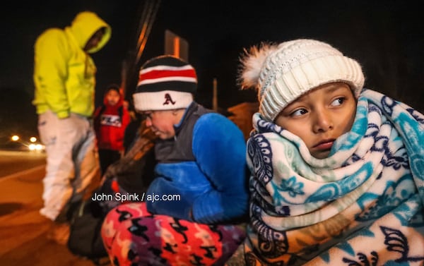 Eight-year-old Nangie Larheta (right) waits for the school bus with her mother, Juana, on Buford Highway in below-freezing temperatures Wednesday morning. JOHN SPINK / JSPINK@AJC.COM