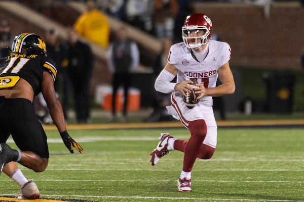 Oklahoma quarterback Jackson Arnold, right, runs around Missouri linebacker Corey Flagg Jr., left, during the first half of an NCAA college football game Saturday, Nov. 9, 2024, in Columbia, Mo. (AP Photo/L.G. Patterson)