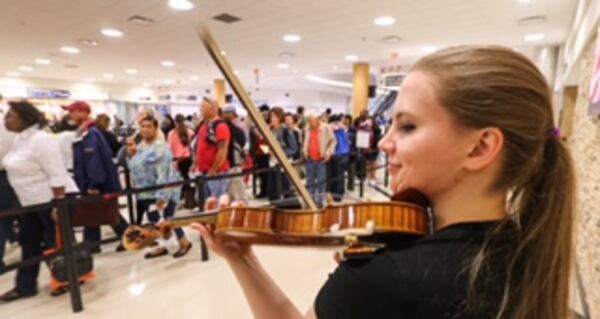 Spink airport photo Jennifer Warrilow soothes tension of fliers in long lines with violin music. John Spink / AJC