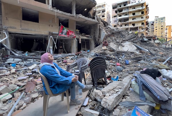 A woman sits on the rubble as she looks to a building destroyed by an Israeli airstrike in Dahiyeh, in the southern suburb of Beirut, Lebanon, Monday, Nov. 11, 2024. (AP Photo/Hussein Malla)