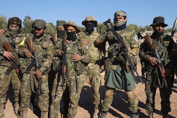 Syrian opposition soldiers stand in formation after entering the village of Anjara, western outskirts of Aleppo, Syria, Thursday Nov. 29, 2024. Syrian armed groups launched a large-scale attack on areas controlled by government forces and seized territory in northwestern Syria, opposition groups said Thursday.(AP Photo/Omar Albam)