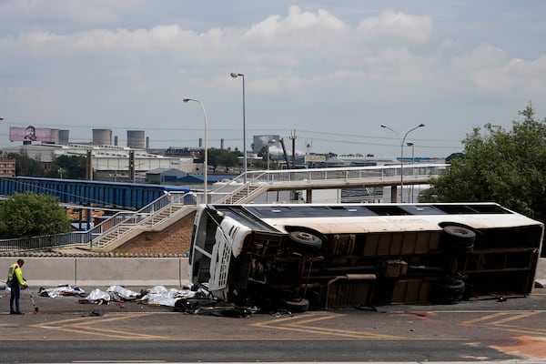 A forensic officer investigate a bus that overturned on a highway in Johannesburg, South Africa, Tuesday, March 11, 2025, killing multiple people and injuring some. (AP Photo/Alfonso Nqunjana)