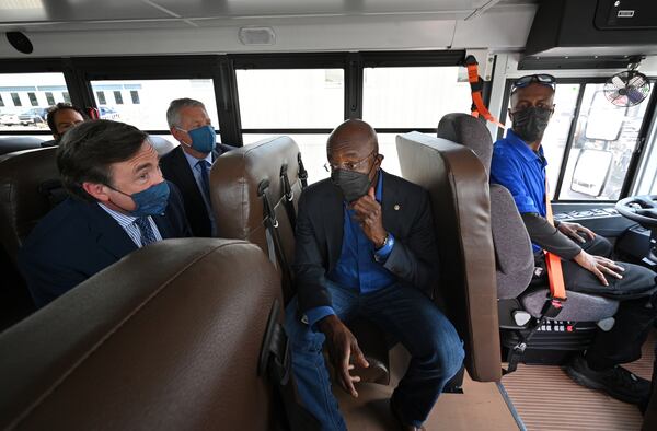 Sen. Raphael Warnock (center) talks with Trevor Rudderham (left), senior vice president for product planning and electrification for Blue Bird, and Phil Horlock (second from left), president and CEO, during a test ride on an electric school bus in Fort Valley on Tuesday, May 4, 2021. (Hyosub Shin / Hyosub.Shin@ajc.com)