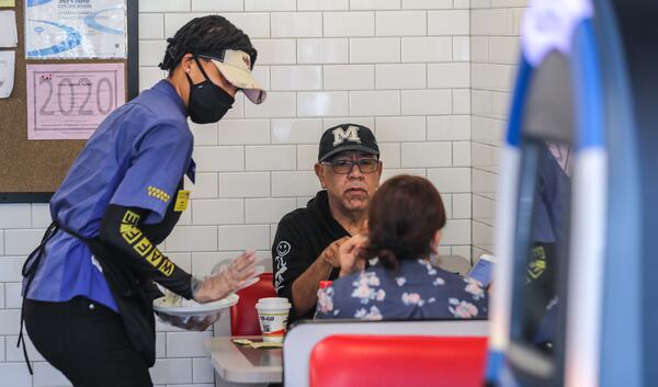 Waffle House's Miss D (left) serves Daniel Bahena and his guest (right) on Monday, April 27, 2020 at The Waffle House at 2886 Clairmont Road in Brookhaven. Restaurants around metro Atlanta began to reopen dining rooms Monday, April 27, 2020 as restrictions related to the coronavirus pandemic are lifted. JOHN SPINK/JSPINK@AJC.COM