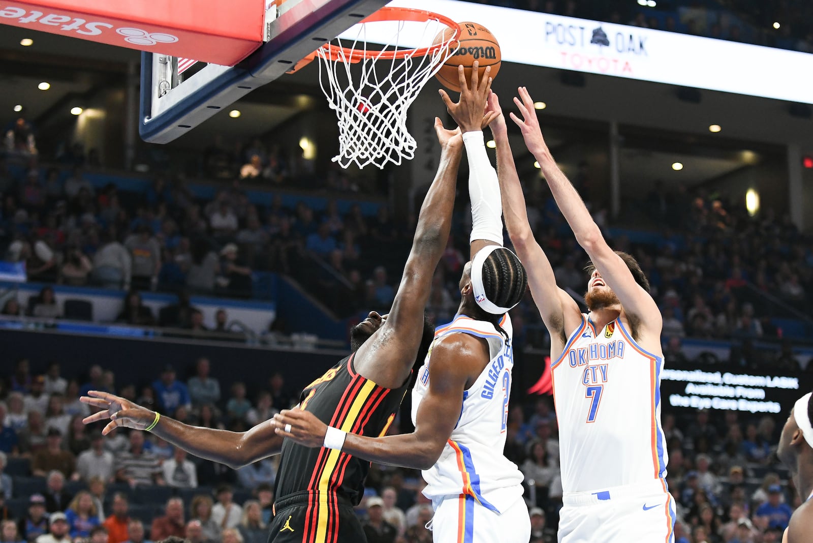 Atlanta Hawks center Clint Capela, left, tries to get to a rebound before Oklahoma City Thunder guard Shai Gilgeous-Alexander, middle, and forward Chet Holmgren, right, during the first half of an NBA basketball game, Sunday, Oct. 27, 2024, in Oklahoma City. (AP Photo/Kyle Phillips)