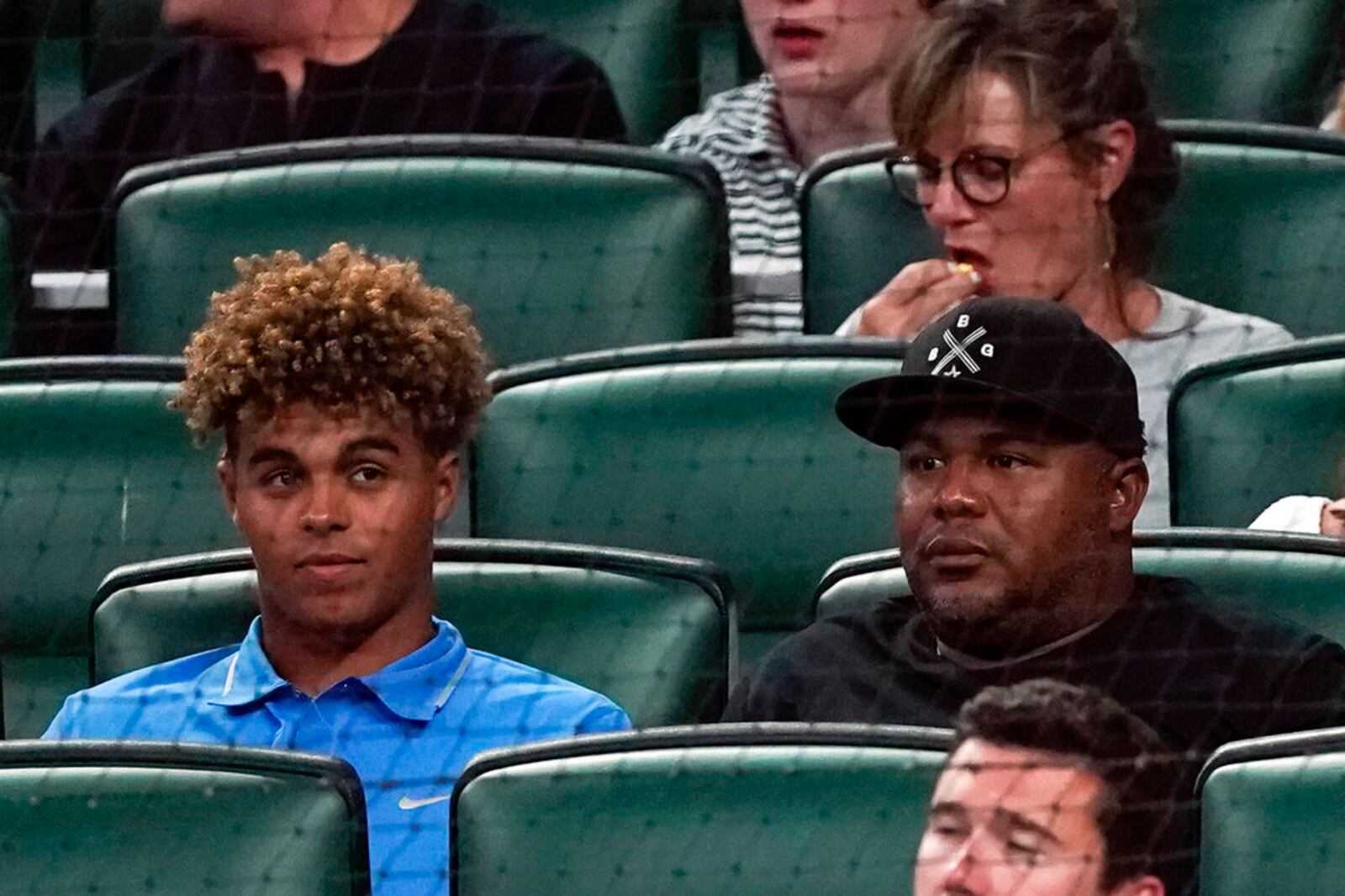 Former Atlanta Braves outfielder Andruw Jones, right, sits with his son Druw during a baseball game between Oakland Athletics and the Braves Tuesday, June 7, 2022, in Atlanta. Druw is a top prospect. (AP Photo/John Bazemore)