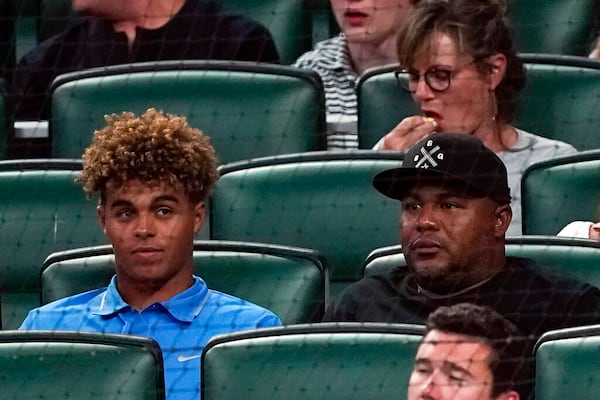 Former Atlanta Braves outfielder Andruw Jones, right, sits with his son Druw during a baseball game between Oakland Athletics and the Braves Tuesday, June 7, 2022, in Atlanta. Druw is a top prospect. (AP Photo/John Bazemore)