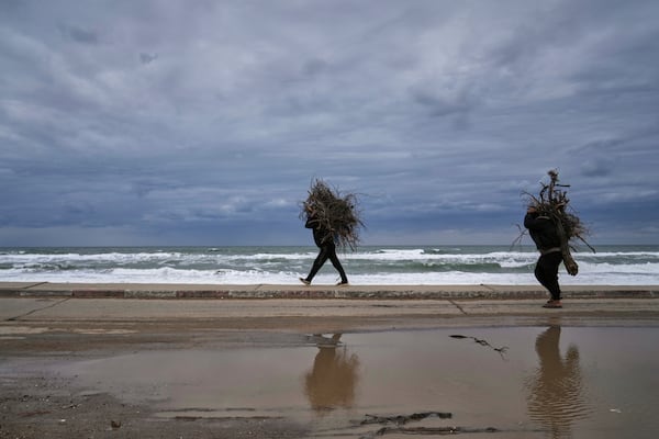 Palestinians carry bundles of wood as they walk along a beach road leaving northern Gaza during the renewed Israeli army offensive in the Gaza Strip, Friday March 21, 2025. (AP Photo/Abdel Kareem Hana)