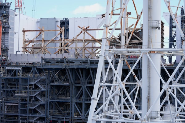 The damaged Unit 1 reactor, back, and the exhaust stack shared by the Unit 1 and 2 reactors are seen at the Fukushima Daiichi nuclear power plant, run by Tokyo Electric Power Company Holdings (TEPCO), in Okuma town, northeastern Japan, on Monday Feb. 20, 2025. (AP Photo/Eugene Hoshiko)