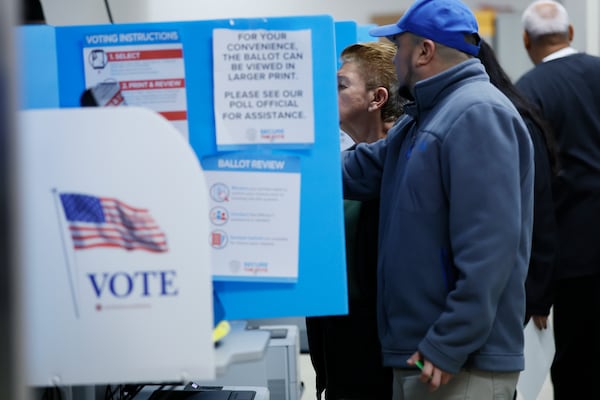 A production line worker at Shaw carpet factory, William Raguay, assists his mother, Emma Medina, in casting her vote at the Dalton Courthouse side on Wednesday, October 19, 2022. Miguel Martinez / miguel.martinezjimenez@ajc.com