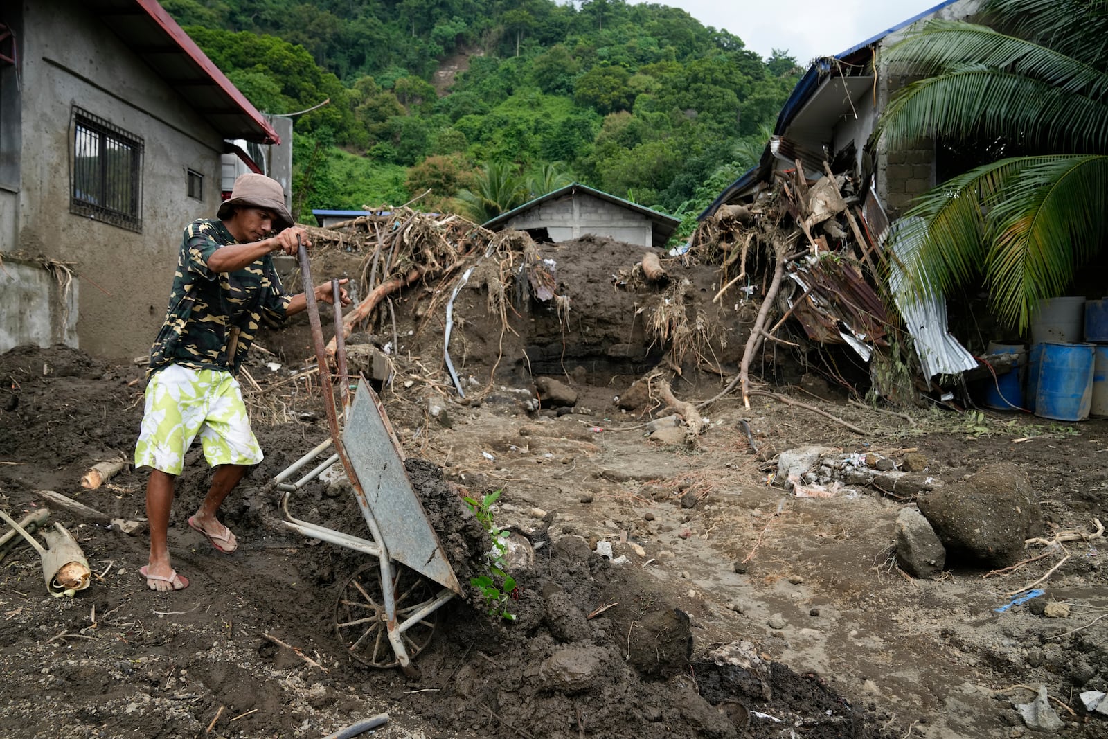 A resident cleans out mud from his damaged home as it was struck by a landslide triggered by Tropical Storm Trami on Saturday, Oct. 26, 2024, in Talisay, Batangas province, Philippines. (AP Photo/Aaron Favila)