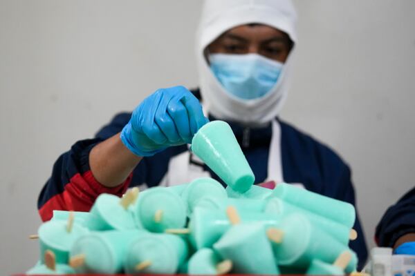 A worker packages popsicles at an artisanal factory in Salcedo, Ecuador, Thursday, Nov. 28, 2024, amid a wave of power outages, triggered by a prolonged dry spell. (AP Photo/Dolores Ochoa)