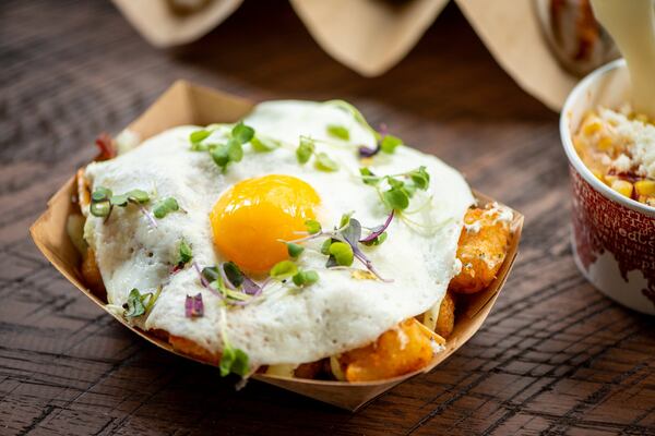 Crisp Tots and Local Egg side with herb goat cheese, smoked cheddar, avocado crema, chile butter, peppered bacon, and micro greens. Photo credit- Mia Yakel.