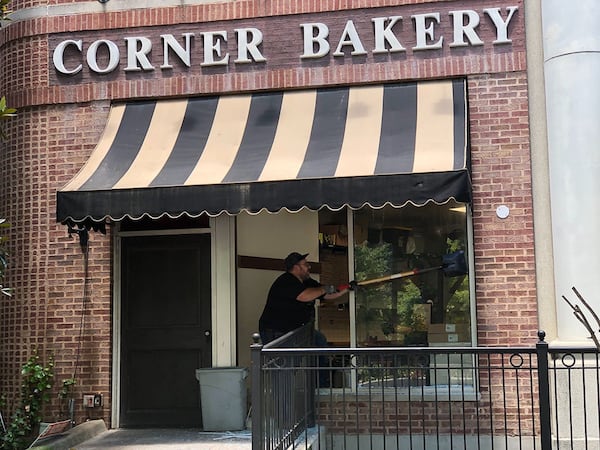 Staff at Corner Bakery cleaning up debris and glass from events of Friday night. (Leon Stafford / Leon.Stafford@ajc.com)