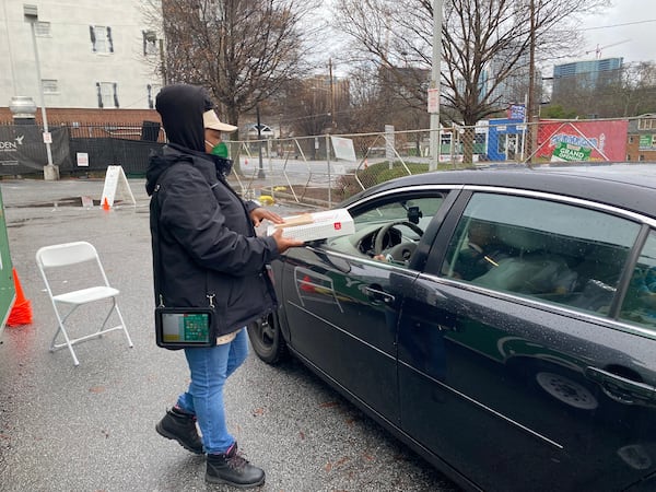 Lavenus Fulton hands a customer an order of Krispy Kreme doughnuts at the pop-up location on Ponce de Leon in Midtown Atlanta. Ligaya Figueras/ligaya.figueras@ajc.com