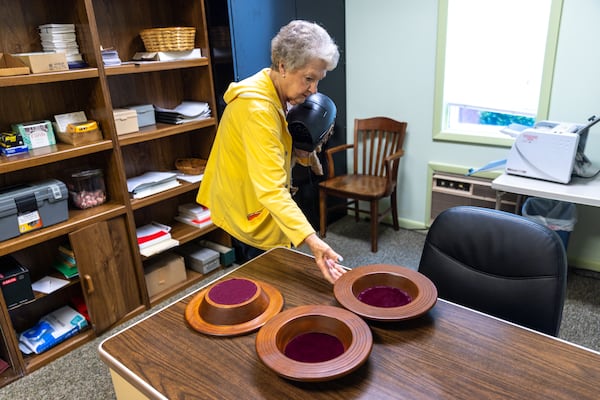 Nelle Ariail handles offering trays made and signed by Jimmy Carter inside Maranatha Baptist Church in Plains on Sunday, Feb. 26, 2023. (Arvin Temkar/AJC)