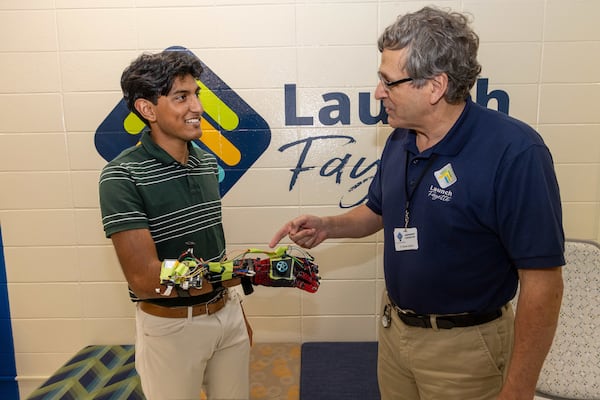 Aadi Vaidya (left) talks with Launch Fayette director Steve Justice about the glove he developed to help reduce tremors in people with Parkinson's disease. PHIL SKINNER FOR THE ATLANTA JOURNAL-CONSTITUTION