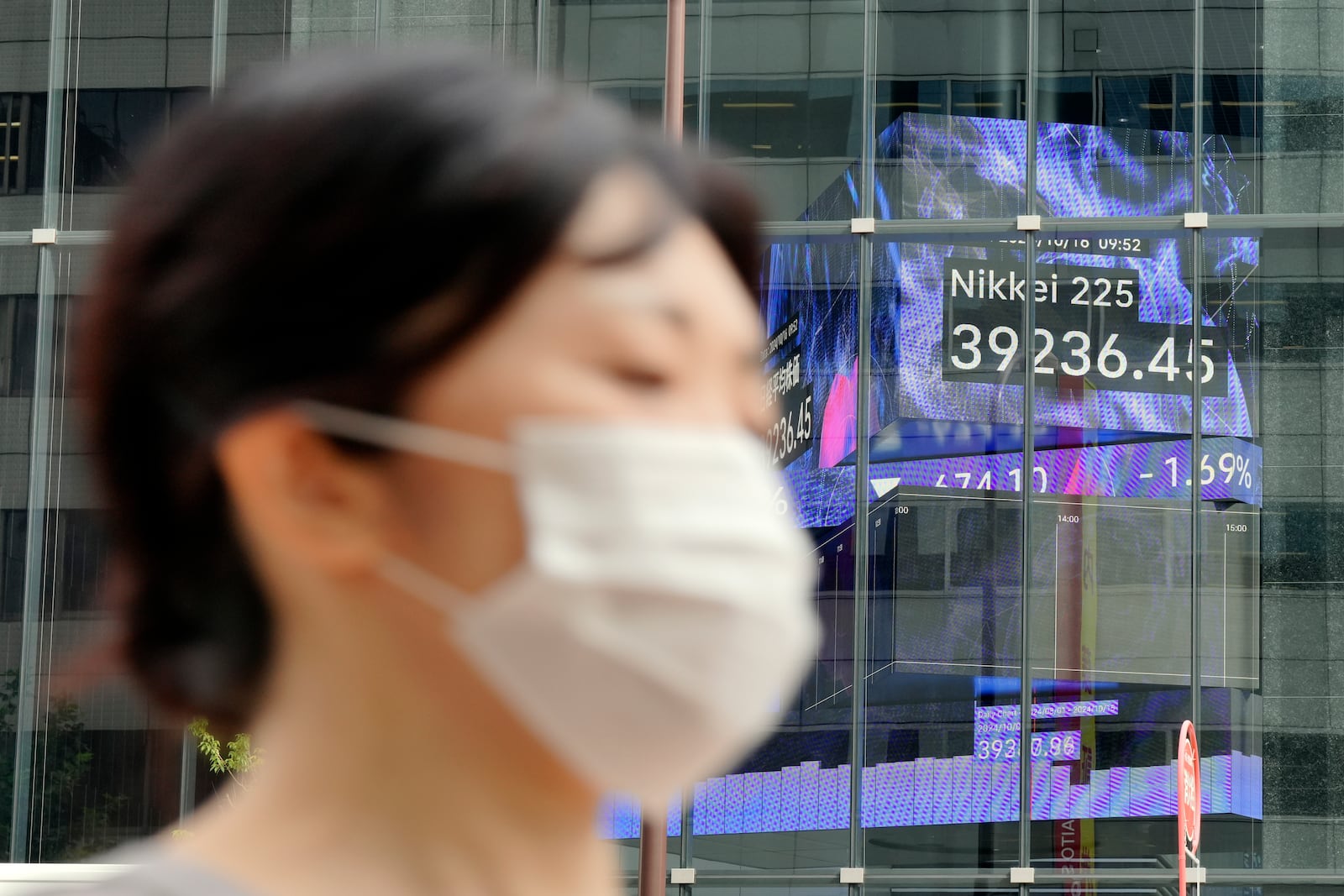 A person walks near an electronic stock board showing Japan's Nikkei index at a securities firm Wednesday, Oct. 16, 2024, in Tokyo. (AP Photo/Eugene Hoshiko)