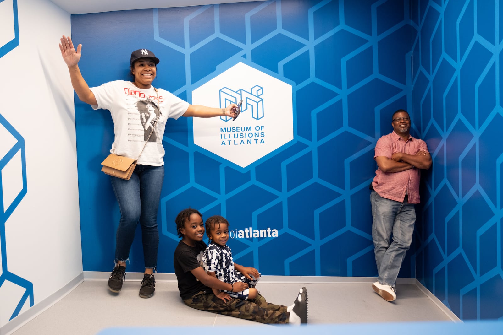 The Curry family, Devoria, from left, Aiden, Kaceson and Raymond, play in the Ames room at the Museum of Illusions Atlanta in Atlantic Station on Sunday, May 21, 2023.  (Ben Gray / Ben@BenGray.com)