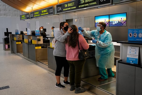 FILE - Licensed vocational nurse Caren Williams, left, collects a nasal swab sample from a traveler at a COVID-19 testing site at the Los Angeles International Airport in Los Angeles, Monday, Nov. 23, 2020. (AP Photo/Jae C. Hong, File)