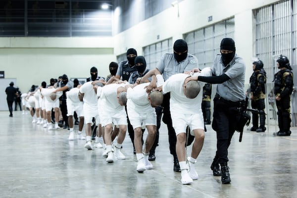 In this photo provided by El Salvador's presidential press guards, prison guards transfer deportees from the U.S., alleged to be Venezuelan gang members, to the Terrorism Confinement Center in Tecoluca, El Salvador, Sunday, March 16, 2025. (El Salvador presidential press office via AP)