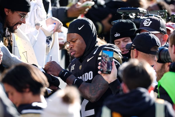 Colorado wide receiver Travis Hunter, center, gives an autograph while heading to the locker room after an NCAA college football game against Oklahoma State, Friday, Nov. 29, 2024, in Boulder, Colo. (AP Photo/David Zalubowski)