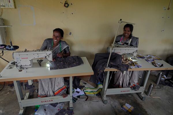 H. Gauri, 32, right, and S. Jayalakahmi laugh as they use electric sewing machines to stitch clothes in a small garage, at the campus of the Swami Vivekananda Youth Movement, a nonprofit that works to help poor and Indigenous communities, in Kenchanahalli, India, Monday, Sept. 23, 2024. (AP Photo/Aijaz Rahi)