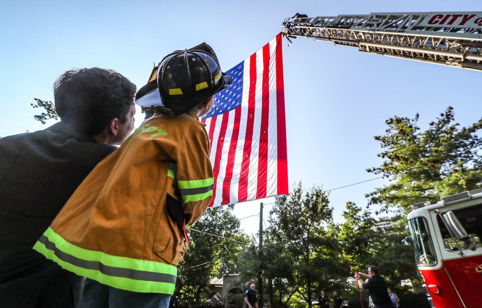 September 11, 2023 Atlanta: Mark Colker-4 (right) was all dressed out to see his favorite firefighters alongside his father, Steven Cocker (left) who works in the music department at the Cathedral of Christ the King as they both watched Atlanta firefighters post an American flags between two ladder trucks. Atlanta police and firefighters were in attendance on Monday, September 11, 2023 at the Cathedral of Christ the King, 2699 Peachtree Road, NE in Buckhead in observance of the Blue Mass. The annual Mass honors public safety officials and first responders. City of Atlanta Mayor, Andre Dickens, along with police, fire officials and honor guards participated in the solemn Mass led by Rector, Monsignor Francis G. McNamee. Wreaths were posted in front of the of the church, honoring those who lost their lives on Sept. 11, 2001. The Blue Mass tradition began in 1934, when a priest from the Archdiocese of Baltimore, Father Thomas Dade formed the Catholic Police and Firemen’s Society. (John Spink / John.Spink@ajc.com)

