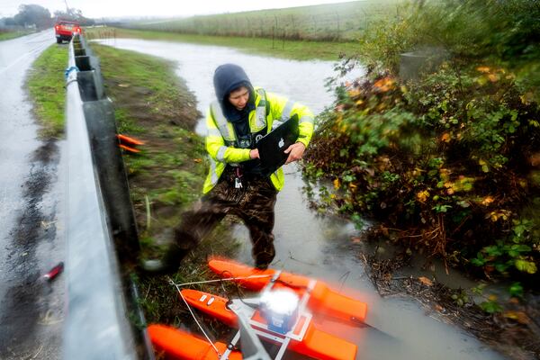 U.S. Geological Survey Hydrologic technician Isabella Karamitsos works to deploy a sensor to measure water flow as heavy rains impact Santa Rosa, Calif., on Wednesday, Nov. 20, 2024, (AP Photo/Noah Berger)