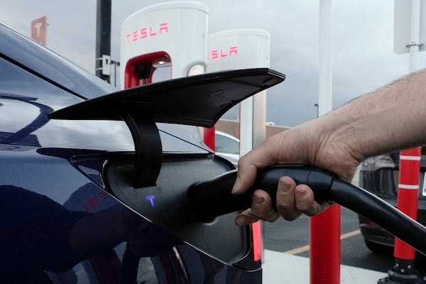 FILE - A motorist charges his electric vehicle at a Tesla Supercharger station in Detroit, Nov. 16, 2022. (AP Photo/Paul Sancya, File)