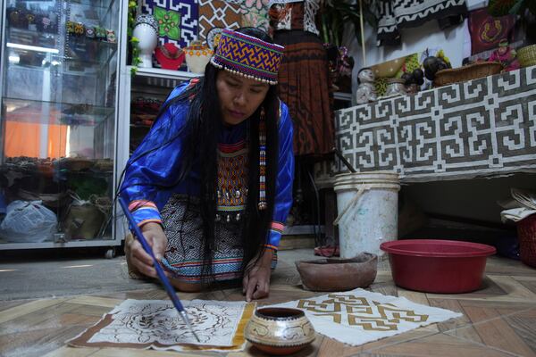 Sadith Silvano, from Paoyhan, a Shipibo-Konibo Indigenous community in the Amazon, paints a tablecloth at her home and workshop in Lima, Peru, Saturday, Oct. 19, 2024. Handpainted textiles like the ones she crafts, known as “kené,” have slowly gained recognition and were declared part of the “Cultural Heritage of the Nation” by the Peruvian government in 2008. (AP Photo/Guadalupe Pardo)