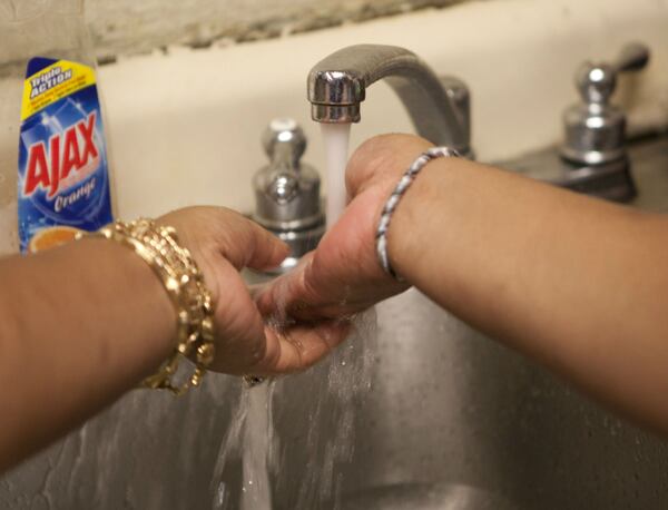 In this Jan. 31, 2011, photo, Gina Nikichiw-Spell feels cold water flowing out of the kitchen tap at Mayor Wright Housing in Honolulu.