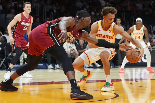 Miami Heat center Bam Adebayo (13) and Atlanta Hawks guard Dyson Daniels (5) go after a loose ball during the first half of an NBA basketball game, Wednesday, Feb. 26, 2025, in Miami. (AP Photo/Marta Lavandier)