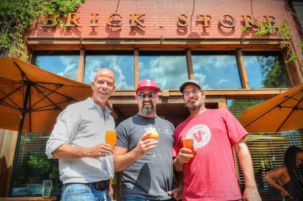 Partners Dave Blanchard (from left), Mike Gallagher and Tom Moore share a toast in front of the Brick Store Pub at 125 E. Court Square in Decatur. CHRIS HUNT / SPECIAL