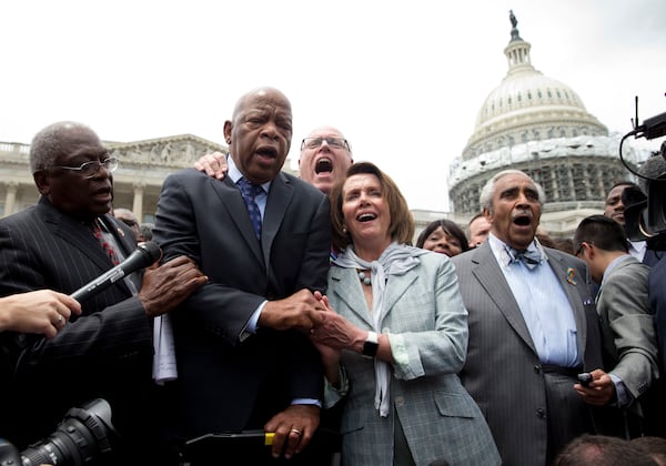 U.S. Rep. John Lewis, D-Atlanta, holds hands with House Minority Leader Nancy Pelosi of California as a group of congressmen sing “We Shall Overcome” on Capitol Hill in Washington after House Democrats ended their 26-hour sit-in protest in June. (AP Photo/Carolyn Kaster)