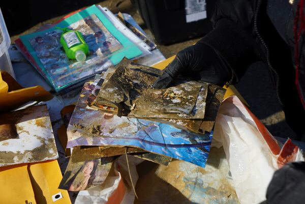 Angela McGee brushes away the dirt from photos she browses over in Jill Holtz' collection on Friday, Feb. 7, 2025, in Swannanoa, N.C. (AP Photo/Allen G. Breed)