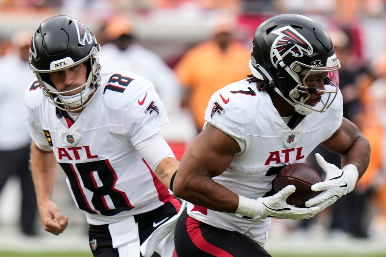 Atlanta Falcons running back Bijan Robinson (7) takes the ball from Atlanta Falcons quarterback Kirk Cousins (18) during the first half of an NFL football game against the Atlanta Falcons, Sunday, Oct. 27, 2024, in Tampa. (AP Photo/Chris O'Meara)