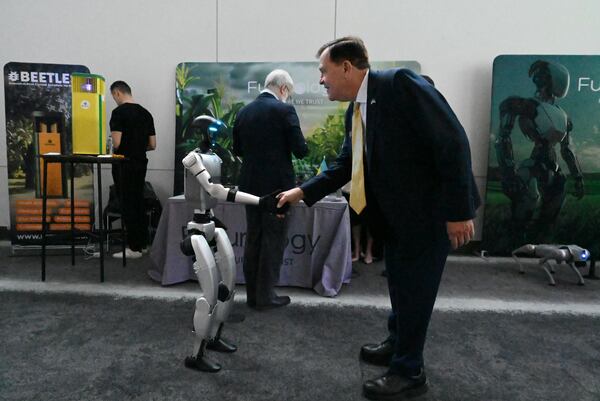 Emory Morsberger, Executive Director of the Gateway85 Community Improvement District, is greeted by Futurology Tech’s Unitree robot during the Launch Pad Tech Collaboration Event hosted with Georgia Tech, Partnership Gwinnett and Peachtree Corners Curiosity Lab on Thursday in Norcross. Hyosub Shin/AJC