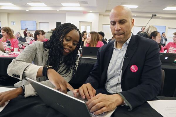 Cory Booker gets some assistance from Esosa Osa in Atlanta on Nov. 21 while texting people on his call list. Democratic presidential candidates including Cory Booker, Amy Klobuchar, Andrew Yang and Pete Buttigieg, along with Stacey Abrahms, were calling and texting voters whose registrations could be canceled in Georgia at a Fair Fight phone bank at Ebenezer Baptist Church. The phone bank was in response to Georgia election officials’ plan to cancel more than 313,000 voter registrations next month. Bob Andres / robert.andres@ajc.com