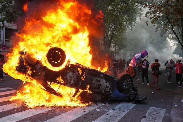 A protester burns a police car during a demonstration by soccer fans join and retirees demanding higher pensions and opposing austerity measures implemented by Javier Milei's government in Buenos Aires, Argentina, Wednesday, March 12, 2025. (AP Photo/Rodrigo Abd)