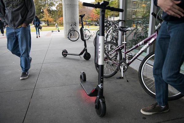 Students walk around Bird scooters near the bicycle rack at Georgia Tech's campus in Atlanta.