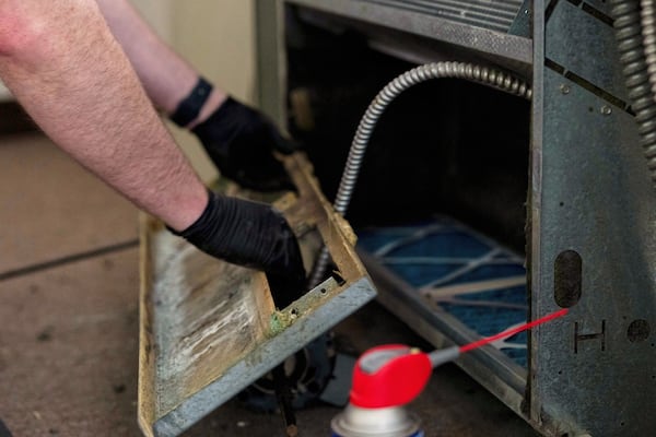 James Richardson takes apart a heating and cooling unit in an apartment being updated at Smith Tower Apartments, on Monday, March 10, 2025, in Vancouver, Wash. (AP Photo/Jenny Kane)