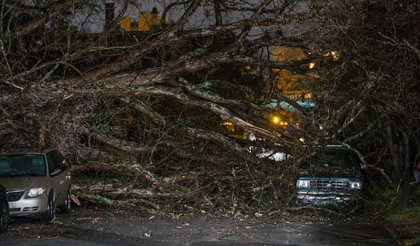 A crew worked Tuesday to restore power after a tree fell onto a home and cars on Linwood Avenue in East Point. BRANDEN CAMP / Special to AJC