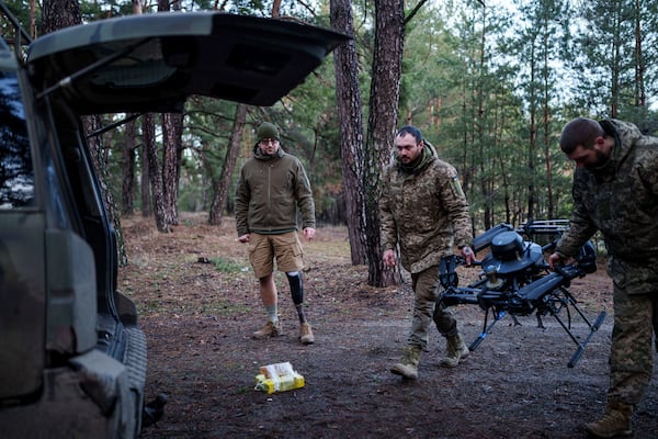 Maksym Vysotskyi, a Ukrainian drone unit commander who lost a leg after stepping on a mine, watches as soldiers load a drone into a car after a test flight in Ukraine's Kharkiv region on Feb. 2, 2025. (AP Photo/Evgeniy Maloletka)