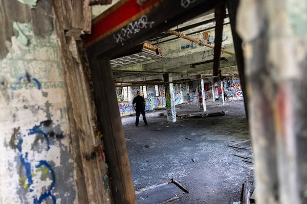 An officer walks through a building at the old prison farm during an Atlanta Police Department and Atlanta Fire Rescue media tour of the site for the proposed Atlanta Public Safety Training Center on Friday, May 26, 2023. (Arvin Temkar / arvin.temkar@ajc.com)