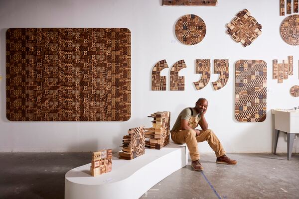 Atlanta artist, Ato Ribeiro, in front of his wood-carved artworks. (Photo provided by Gregory Miller)