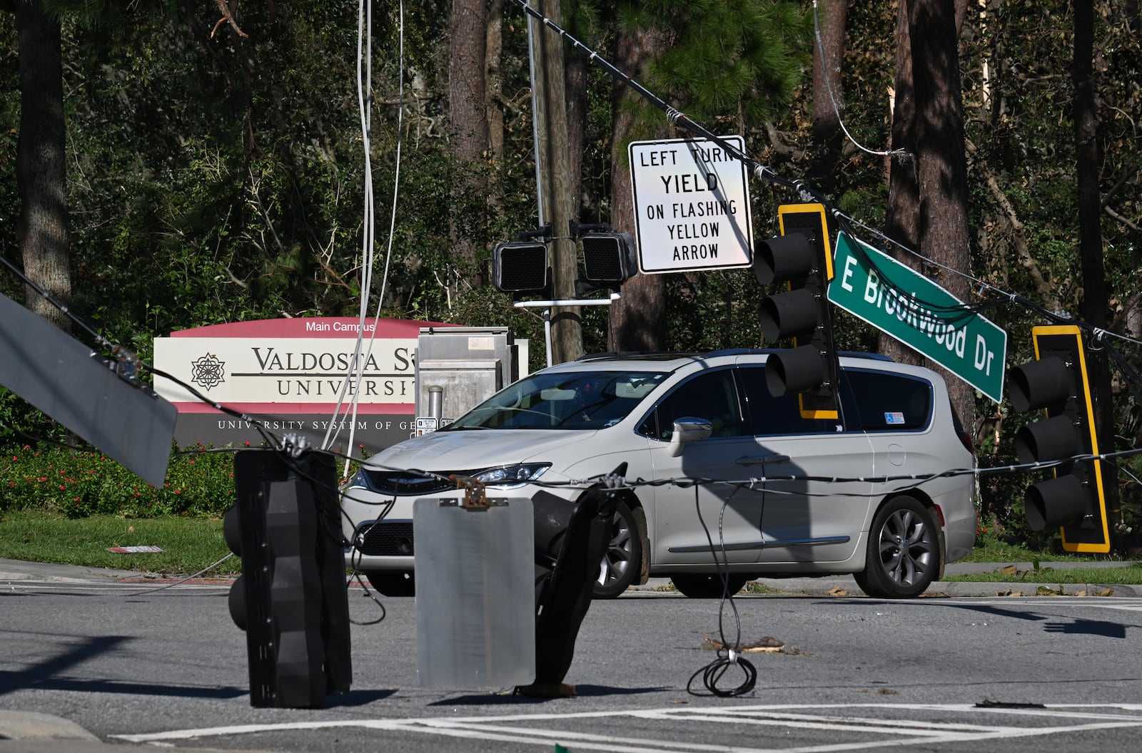 A car drives by fallen traffic signals and wires near Valdosta State University, Saturday, September 28, 2024, in Valdosta. The devastation in Valdosta was extensive after the South Georgia city was battered with hurricane-force winds on Helene’s path across the state. Damaging Helene has swept through Georgia, leading to at least 15 deaths. All 159 counties are now assessing the devastation and working to rebuild, even as serious flooding risks linger. Hyosub Shin/AJC